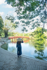 Woman traveller is sightseeing at Huc Bridge spanning Ngoc Son Temple, Hanoi, Vietnam