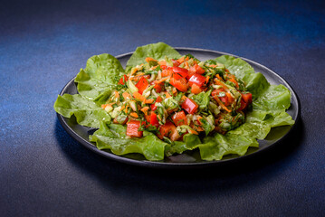 Plate of salad with vegetables and greens on a dark concrete table