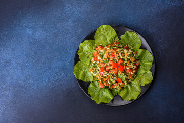 Plate of salad with vegetables and greens on a dark concrete table