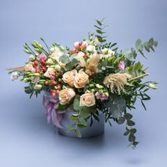 Bouquet in pastel color composed of roses, other different flowers and sprigs of greenery.