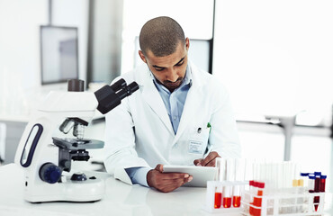 Fototapeta premium Scientist writing DNA results from microscope test on a tablet.Professional male doctor in a lab working with research tubes.Man in a modern laboratory doing medical science data analysis.