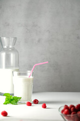homemade cow's milk and raspberries on a light background, milk is a very healthy product that contains calcium, strengthens bones and teeth, healthy nutrition 