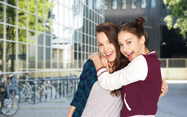 people and friendship concept - happy smiling teenage girls hugging over city street or school yard background