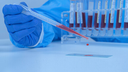 blood is dropped onto a microscope glass slide and blood tubes are the background. Medical research concept