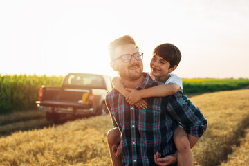 father carrying his son piggyback on wheat field