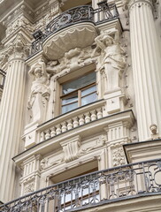 Fototapeta premium The facade of an old building decorated with caryatid sculptures, stucco molding and openwork balconies