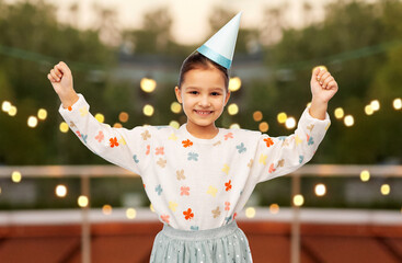 birthday, childhood and people concept - portrait of smiling little girl in dress and party hat...