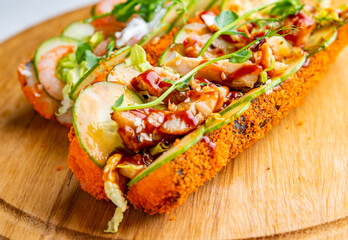 two sushi dog with seafood and vegetables on wooden plate