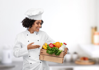 cooking, culinary and people concept - happy smiling female chef in toque holding food in wooden box over restaurant kitchen background