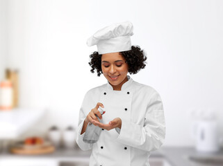 cooking, culinary and people concept - happy smiling female chef applying hand sanitizer or liquid...