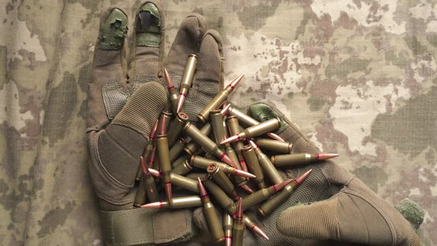 old worn out tactical gloves and machine gun bullets on top of them. soldier's equipment. preparation for loading a weapon by an infantryman.