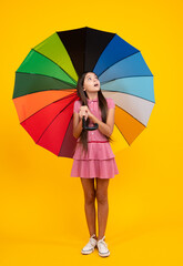 Shocked surprised teenager girl. Summer dress. Happy teen girl holding rainbow umbella standing...