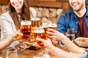 leisure, people and celebration concept - close up of happy friends having dinner and drinking beer at restaurant or pub