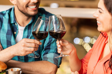 leisure, drinks and people concept - close up of happy couple drinking red wine at restaurant
