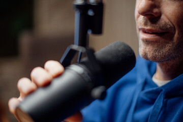 Close-up of mature man speaking in microphone during moderating podcast. - obrazy, fototapety, plakaty
