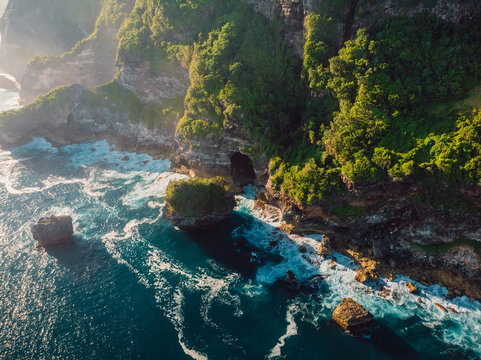 Scenic cliff with fog and ocean with waves in Bali. Aerial view