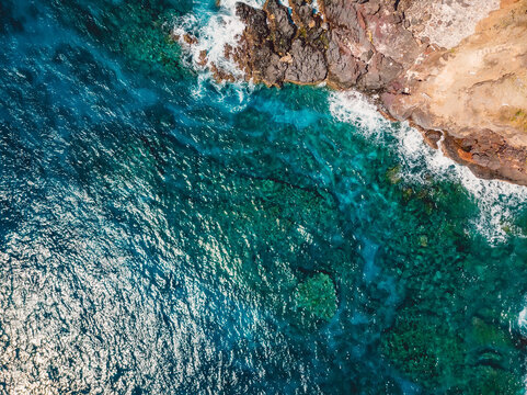 Transparent ocean with rocky coastline in sunny day. Aerial view.