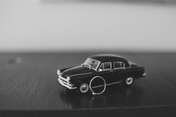 A small car toy on a wooden background. Black and white photo. Model little car.