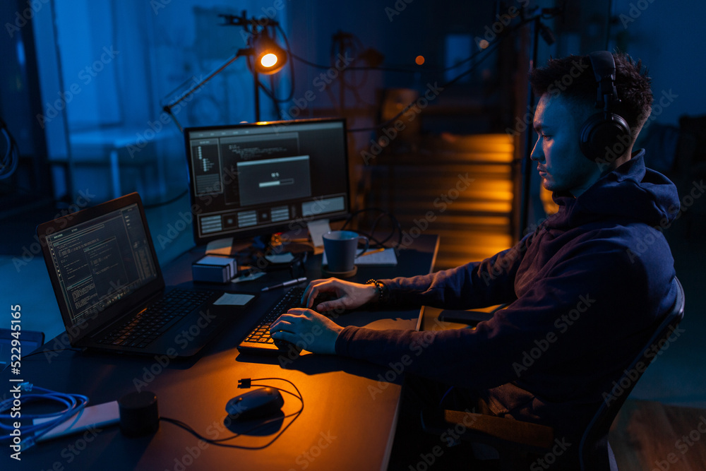 Poster cybercrime, hacking and technology concept - male hacker in dark room writing code or using computer
