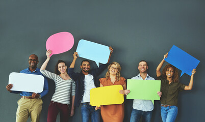 Smiling casual team of diverse people holding opinion speech bubbles, to voice their important...