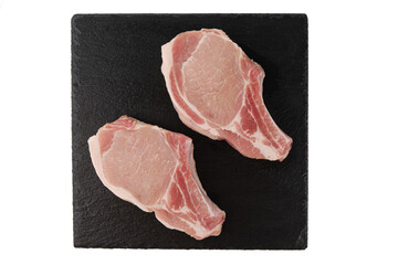 Two pork chops on black slate plate isolated on white background. Top view, flat lay.