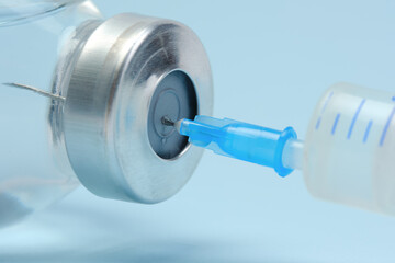 Taking medication into a syringe for injection. Closeup macro. Blue background.