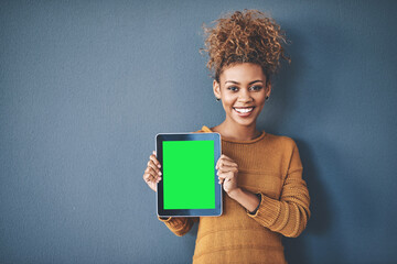 African female holding green screen tablet copyspace. Cute, attractive and smiling young afro woman standing and showing a mobile device.Happy, cheerful and ethnic woman after buying new app. - Powered by Adobe