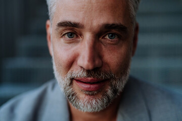 Close-up portrait of handsome businessman sitting out, looking at camera.