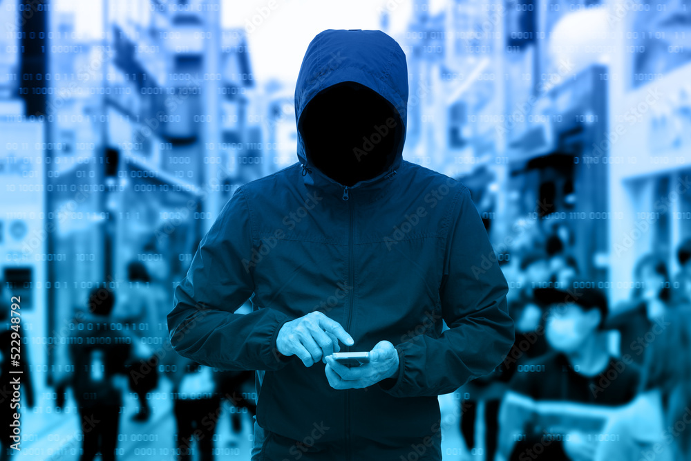 Wall mural Anonymous man in a black hoodie using smartphone hacking. - Wall murals