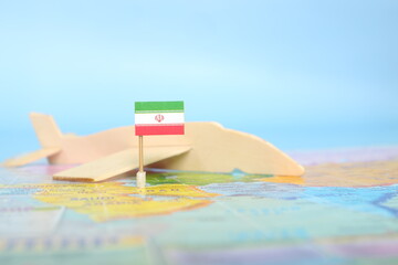 Selective focus of Iranian flag in blurry world map and wooden airplane model. Iran as travel and tourism destination concept.