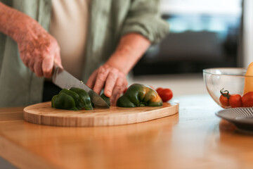 Close-up of senior man preparing vegetable, cutting at wooden board, healthy lifestyle concept.