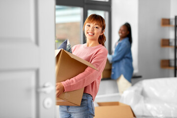 moving, people and real estate concept - happy smiling women with boxes at new home