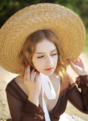 Portrait of pretty blonde girl in straw hat posing on a background of the city.