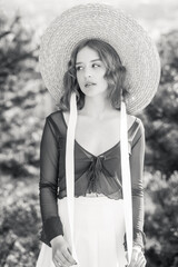 Black and white portrait of stylish girl in straw hat posing on a background of the city.