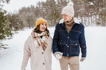 people, love and leisure concept - happy smiling couple walking in winter forest