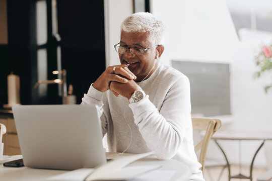Happy senior businessman attending an online meeting at home