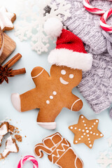 Gingerbread man, cookies and Christmas decor on pastel background.