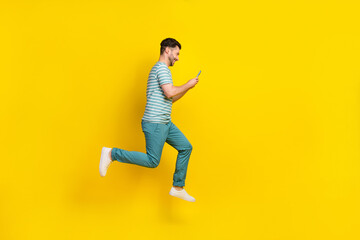 Full length photo of funny guy run type telephone wear t-shirt jeans boots isolated on yellow color background