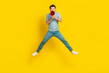 Full length photo of crazy man student dressed striped t-shirt blue trousers screaming in loudspeaker isolated on yellow color background