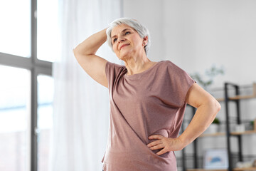 sport, fitness and healthy lifestyle concept - smiling senior woman exercising at home