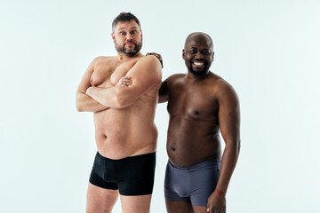 Fototapeta na wymiar two multiethnic men posing for a male edition body positive beauty set. Shirtless guys with different age, and body wearing boxers underwear