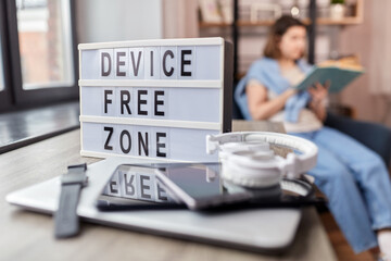digital detox and leisure concept - close up of device free zone words on light box, gadgets on...