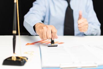 professional businessman hand holding stamp on paperwork or document finance indoor at office, man manager person imprint approved on paper clipboard and signature agreement business