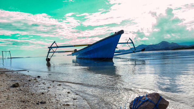 long boat made of blue fiber.  he was parked on the edge of a fine white sandy beach with clear sea water at Ratu Beach, Boalemo Regency, Gorontalo Province.  Outdoor photo taken on August 11, 2022