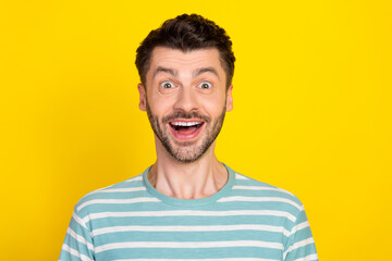 Closeup photo of young attractive guy smiling shock excited looking you isolated on yellow color...