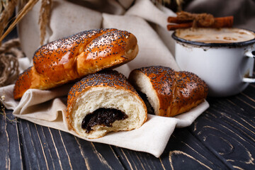 Freshly baked fragrant homemade buns with jam on rustic wooden table.