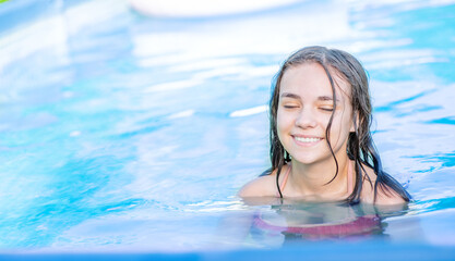 Enjoying teen girl swimming in the pool at sunny day. Empty space for text