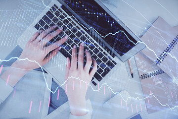 Double exposure of woman hands working on computer and forex graph hologram drawing. Top View. Financial analysis concept.