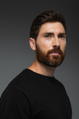 portrait of good-looking bearded man in black t-shirt isolated on grey.