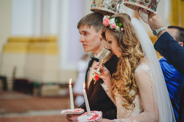 Bride drinking with the cup the blood of God, wine. Newlyweds, couple happy at the wedding ceremony in the church.